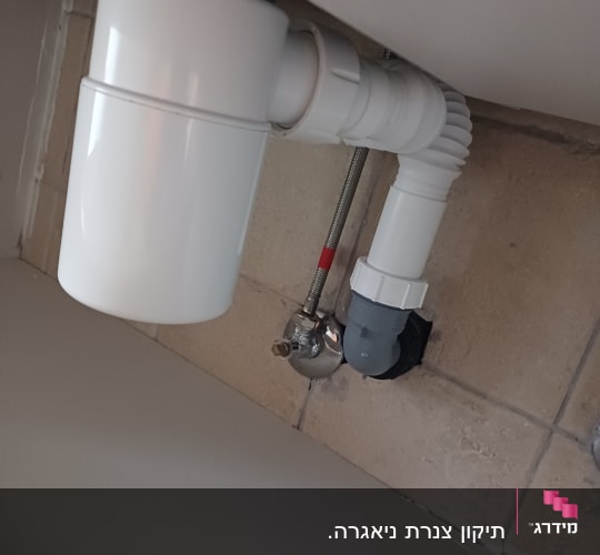 צינור ניקוז לבן מתחת לכיור עם חיבורים